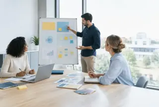 Trois professionnels construisent ensemble une stratégie de marque autour d’un tableau organisé dans une salle de réunion lumineuse.